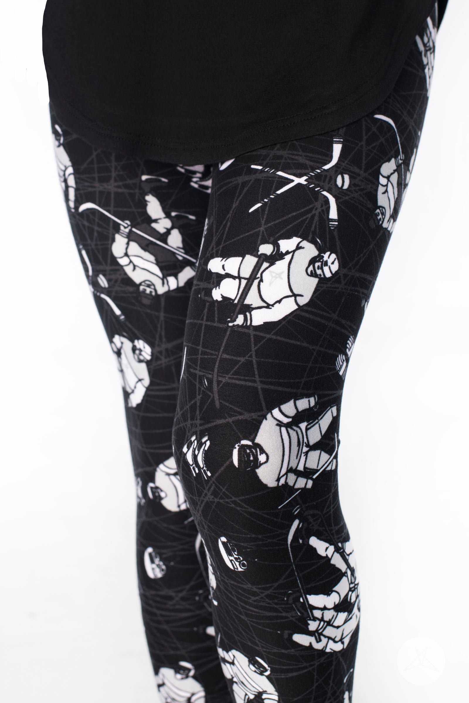 Close-up of SweetLegs Breakaway Kids leggings with black fabric and white hockey player illustrations in action pose